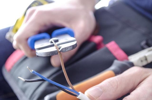Un électricien dépouille d'un fil électrique.