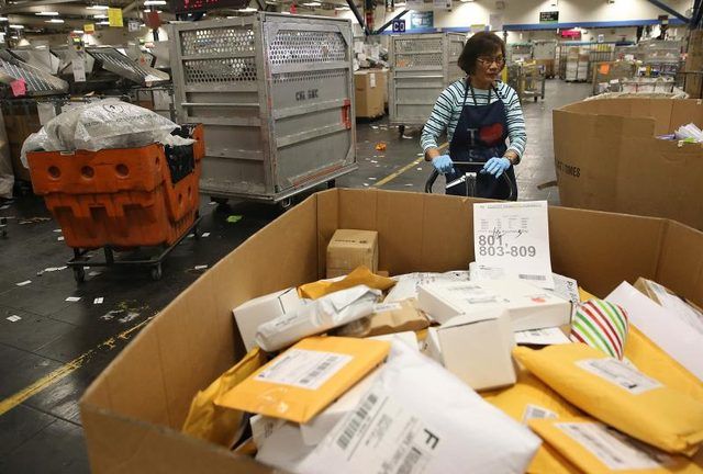 Un travailleur postal États-Unis se déplace un récipient de colis