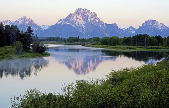 Les tétons se reflètent sur un flux dans le Wyoming.