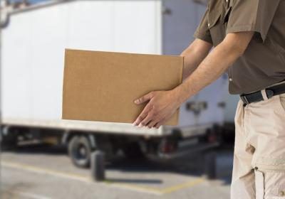 Un employé délivre un camion chargé de boîtes de carton.