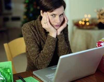 Une femme repose son menton dans ses mains tout en regardant un ordinateur portable.