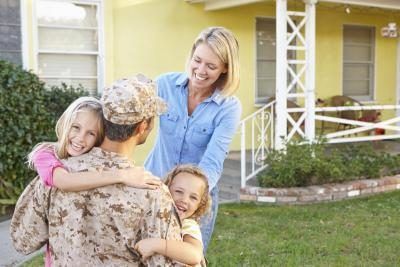 Soldat et la famille embrassant en face de leur maison