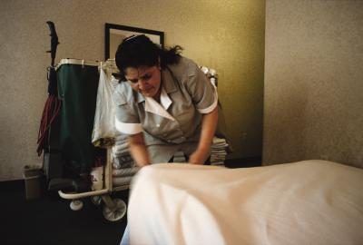 Une femme de ménage nettoie une chambre dans un hôtel.