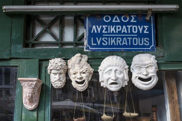 Anciens masques de théâtre grec à base de plâtre accroché en face d'un magasin.
