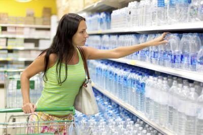 Femme achats pour l'eau en bouteille à l'épicerie